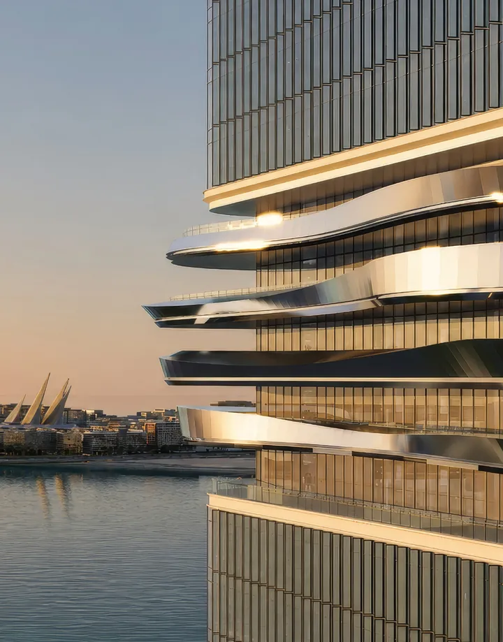 Close-up of the tower’s sculpted silver balcony ribbons catching the sunset over the water