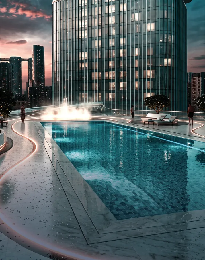 Swimming pool on the podium deck with lit curving paths and the tower above at dusk